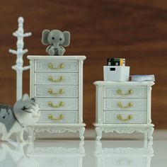 an elephant figurine sitting on top of a dresser next to a toy cat