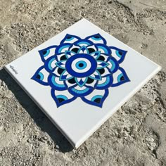 a blue and white tile with an eye in the center sitting on top of some rocks