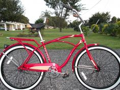 a red bicycle parked on the side of a road next to some grass and trees