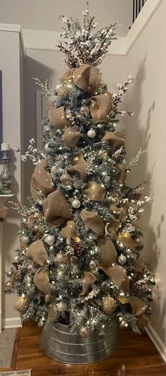 a decorated christmas tree with gold and silver ornaments in a metal bucket on a wood floor