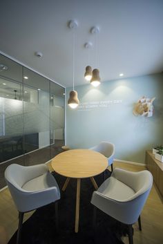 an office with chairs and a table in the center, along with a glass wall behind it