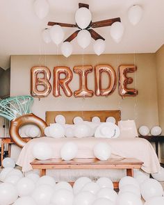 balloons are floating in the air above a table with a large bride balloon on it