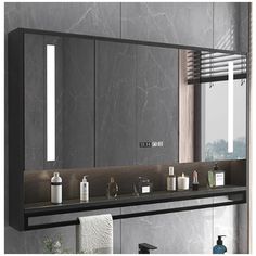 a bathroom vanity with two mirrors and lights on the wall, along with other items in front of it