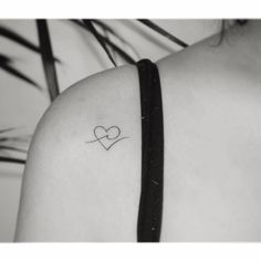 a small tattoo on the back of a woman's shoulder, depicting two hearts