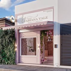 a store front with an awning and flowers on the outside wall, next to a sidewalk