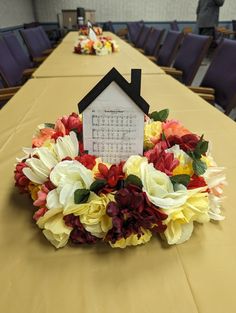 a table with flowers and a house shaped calendar sitting on it's centerpiece