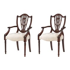 a pair of carved wood chairs with white upholstered cushions