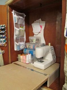 a sewing machine sitting on top of a wooden table next to a shelf filled with craft supplies