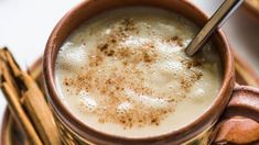 a cup filled with milk and cinnamon sticks