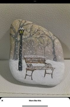 a rock with a bench painted on it and snowing in the park behind it