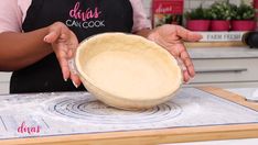 a woman in an apron is holding a bowl on top of a cutting board and preparing food