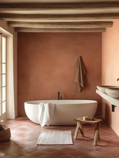 a bath tub sitting next to a sink under a window in a room with pink walls