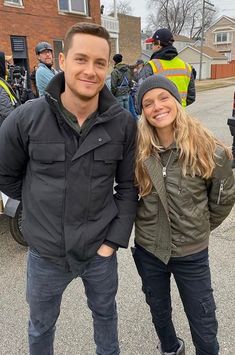 a man and woman standing next to each other in front of some parked motorcycles on the street