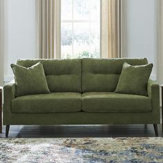 a green couch sitting in front of a window