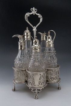 a silver plate with four glass jugs and a pitcher on the bottom one has a heart shaped handle