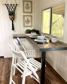 a table with two chairs and plates on it in front of a window that looks out onto the woods