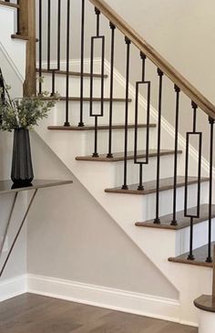 a vase filled with flowers sitting on top of a wooden stair case next to a banister