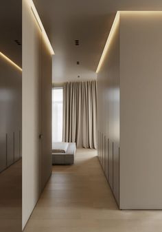 an empty room with white walls and beige curtains on either side of the bed is lit by recessed lights