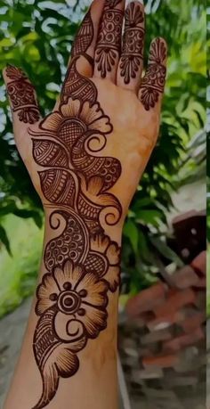 the hand is decorated with henna designs and has an intricate flower pattern on it