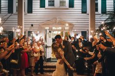 a bride and groom kissing in front of their guests holding sparklers