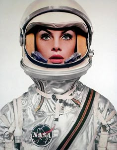 a woman wearing an astronaut's helmet and looking at the camera