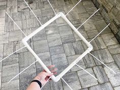 a person is holding up a white object on a brick walkway and it looks like they are trying to pull something out of the ground