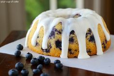 a blueberry bunt cake with icing and fresh blueberries on the side