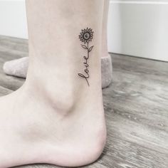 a small sunflower tattoo on the ankle that reads, love and is written in cursive script