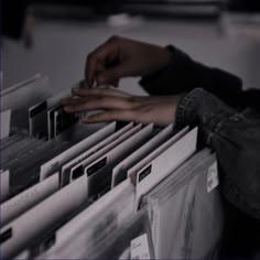 a person's hand on top of a stack of files