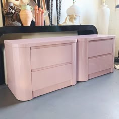 a pink dresser with two drawers in front of a mirror