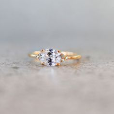 a three stone engagement ring with an oval diamond in the center and two smaller round diamonds on each side