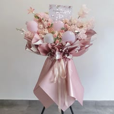 a bouquet of pink and white flowers on a stand with a card in the background