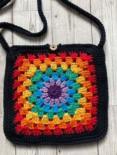 a multicolored crocheted bag sitting on top of a white wooden floor