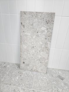 a bathroom with white tile walls and flooring next to a urinal in the corner