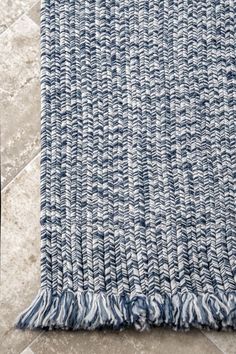 a blue and white rug sitting on top of a floor next to a tile floor