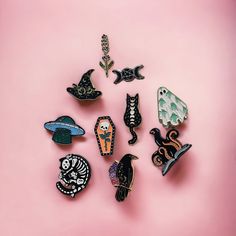 a collection of halloween pins sitting on top of a pink surface