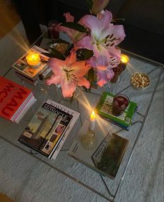 a glass coffee table topped with magazines and flowers