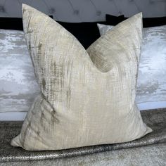 a close up of a pillow on a bed with silver and black pillows in the background