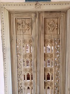 an old wooden door with intricate carvings on the front and side panels, painted white