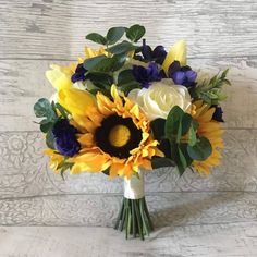 a bouquet of sunflowers and other flowers on a white tablecloth with wood planks