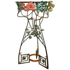 a metal stand with flowers and leaves on it's sides, against a white background