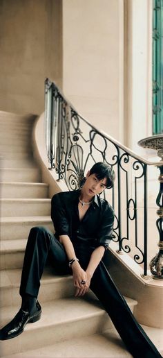 a man sitting on top of a set of stairs next to a metal hand rail