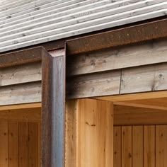 the side of a building with wood siding and metal posts on it's sides