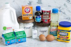 an assortment of ingredients for baking sitting on a counter top next to milk, eggs and flour