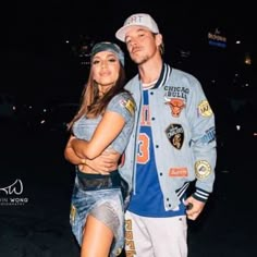 a man and woman standing next to each other in front of a building at night