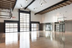 an empty basketball court with glass doors and lights hanging from the ceiling in front of it