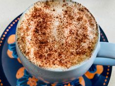 a cappuccino with cinnamon sprinkles is on a blue and orange plate