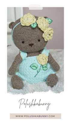 a crocheted teddy bear wearing a blue dress with flowers in it's hair