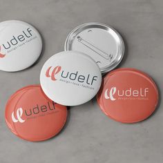 three badges with the name udelf on them sitting next to an orange and white button