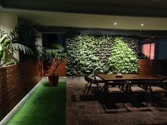 a dining room table and chairs in front of a green wall with plants on it